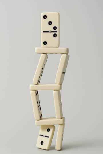 Illustration de l'instabilité du marché immobilier avec une tour de dominos penchée, symbolisant la pression sur les vendeurs et la forte marge de négociation.